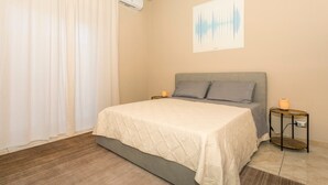 A bedroom with a bed, a bedside table with a candle, a wall-mounted air conditioner, and a sound wave art piece on the wall. - Apartment 'Lemon Terrace' with Private Terrace, Wi-Fi and Air Conditioning (Catania)