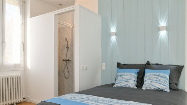 A bedroom with a bed, two wall-mounted lights, a door, and a radiator. - Guest Room 4 with Shared Pool, Communal Garden, and Wi-Fi (Betton-Bettonet)