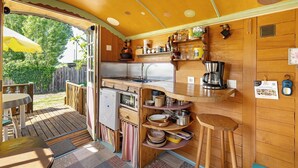 Cozinha compacta com armários de madeira, geladeira, cafeteira e área de jantar com mesa e cadeiras.