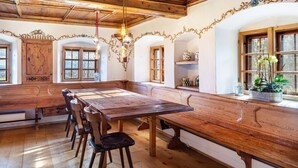 En traditionel spisesal med et træbord, bænk og en lysekrone.