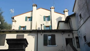 A building with multiple chimneys, a tiled roof, and a balcony with a railing. - 'Ca' Molinetto' Apartment with Wi-Fi and Air Conditioning (Treviso)