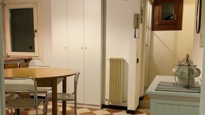 A room with a checkered floor, a wooden table with chairs, a radiator, and a cabinet with a decorative item on top. - 'Ca' Molinetto' Apartment with Wi-Fi and Air Conditioning (Treviso)
