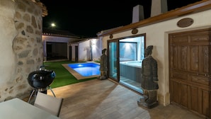 A patio with a barbecue grill, a swimming pool, and a statue.
