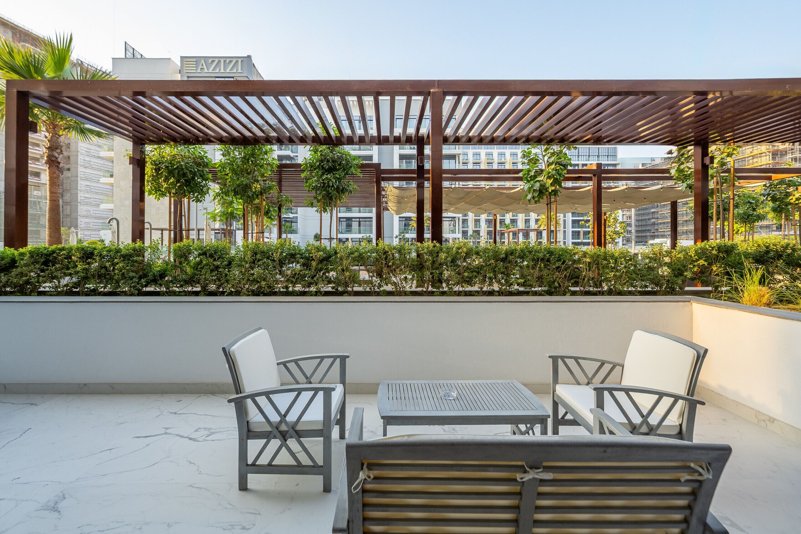 A rooftop terrace with a pergola, seating area, and a view of buildings in the background.