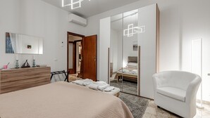Un dormitorio moderno con una cama grande, un sillón blanco, un espejo y un armario.