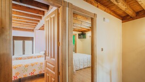 A room with wooden beams, a bed with a floral bedspread, and a white wall.