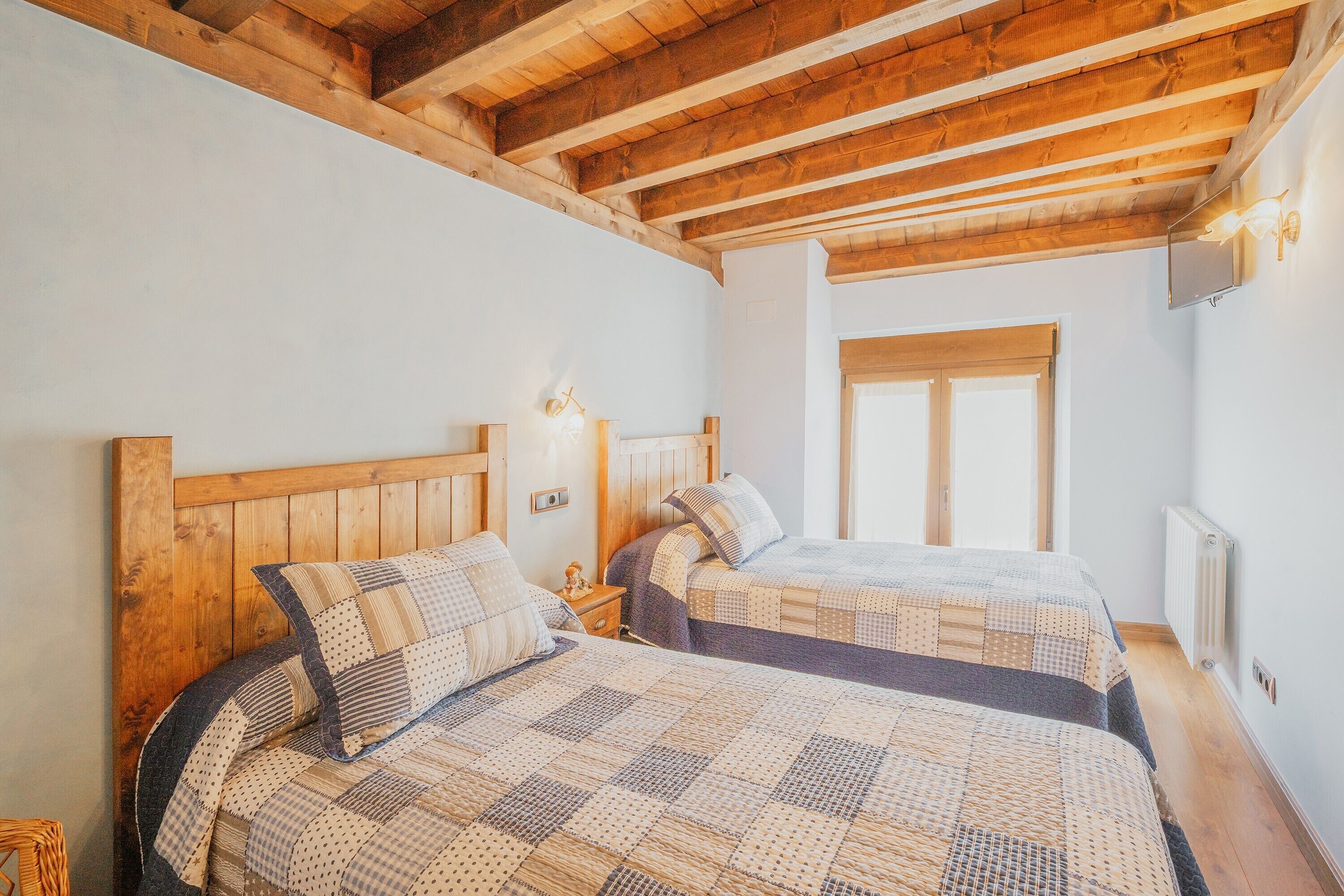 Una stanza con due letti di legno, una finestra e un termosifone.