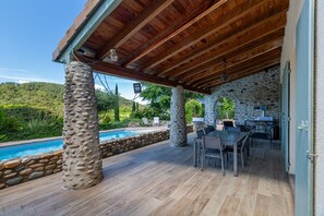 An outdoor patio with a pool, stone pillars, wooden ceiling, and a dining area. - Guest Room “Chambre 3 personnes” with Shared Pool, Wi-Fi & Air Conditioning (Saint-Fortunat-sur-Eyrieux)