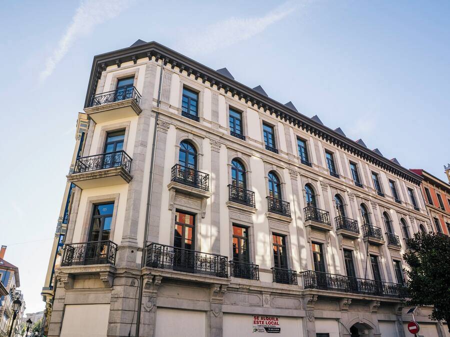 Un edificio de varios pisos con arquitectura clásica, que cuenta con balcones y ventanas grandes.