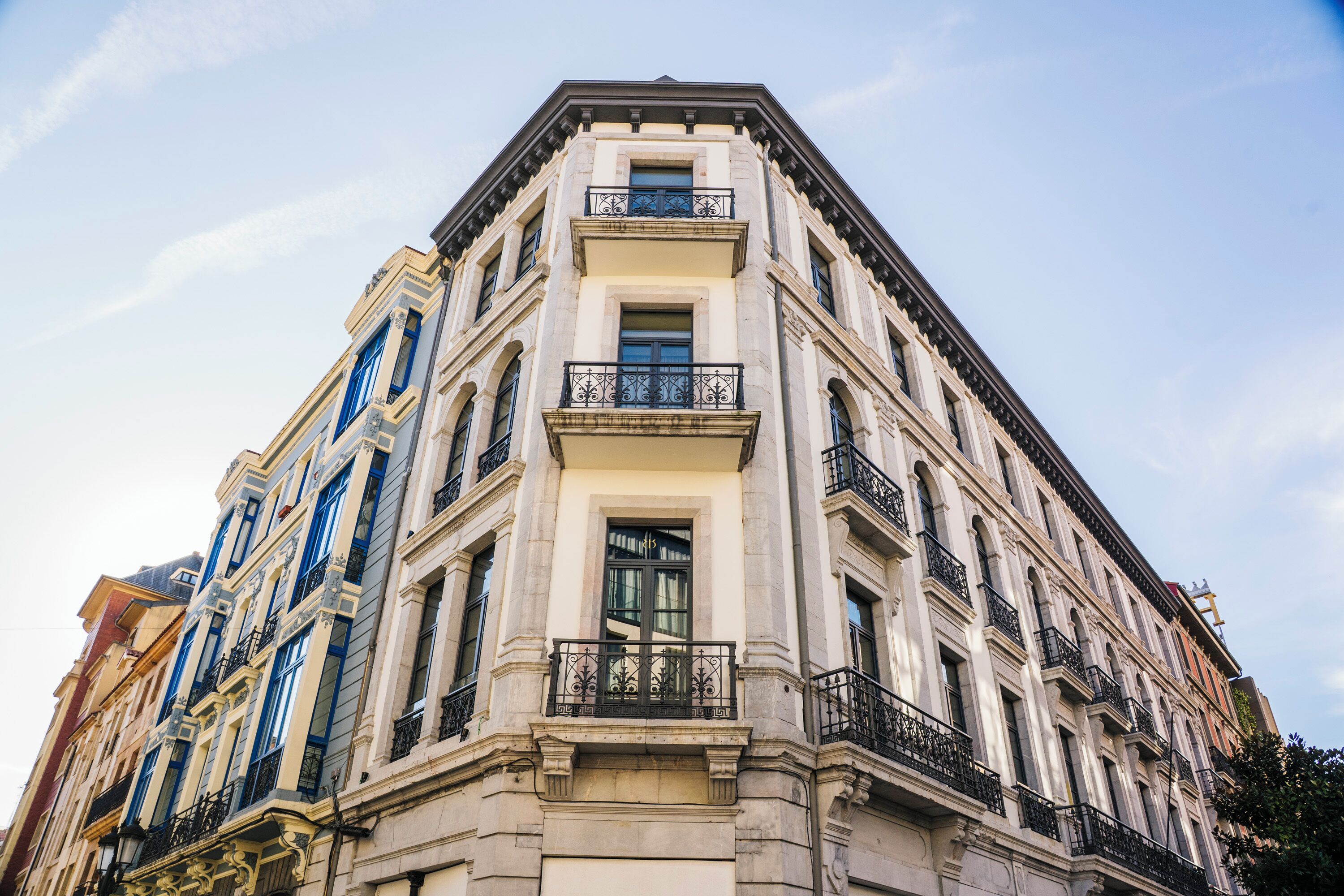 Un edificio en esquina con varios pisos, ventanas amplias y balcones.