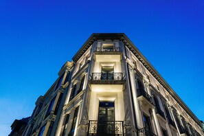 Un immeuble à plusieurs étages de style architectural classique, doté d’une entrée centrale et d’un balcon.