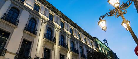 Ein historisches Gebäude mit klassischer Architektur, das mit aufwendigen Balkonen und einem markanten Eingang verziert ist.