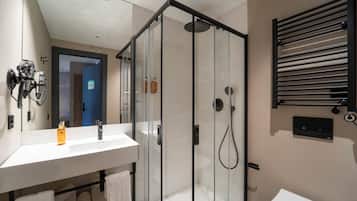 A modern bathroom with a glass-enclosed shower, a white sink, and a towel rack.