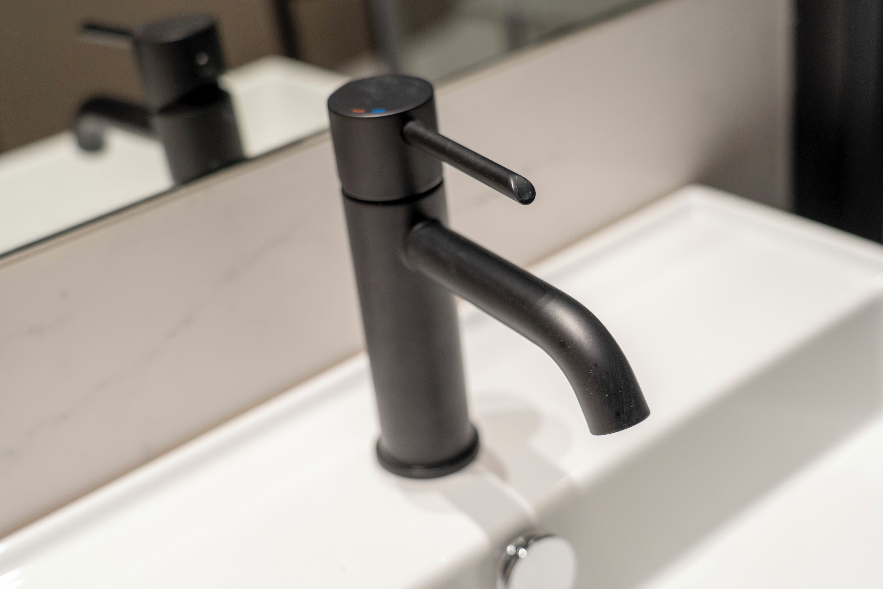 A modern bathroom sink with a sleek faucet and a mirror above it.