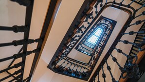 Eine Wendeltreppe mit aufwändig gestalteten Metallgeländern und einem zentralen Glasaufzugsschacht.
