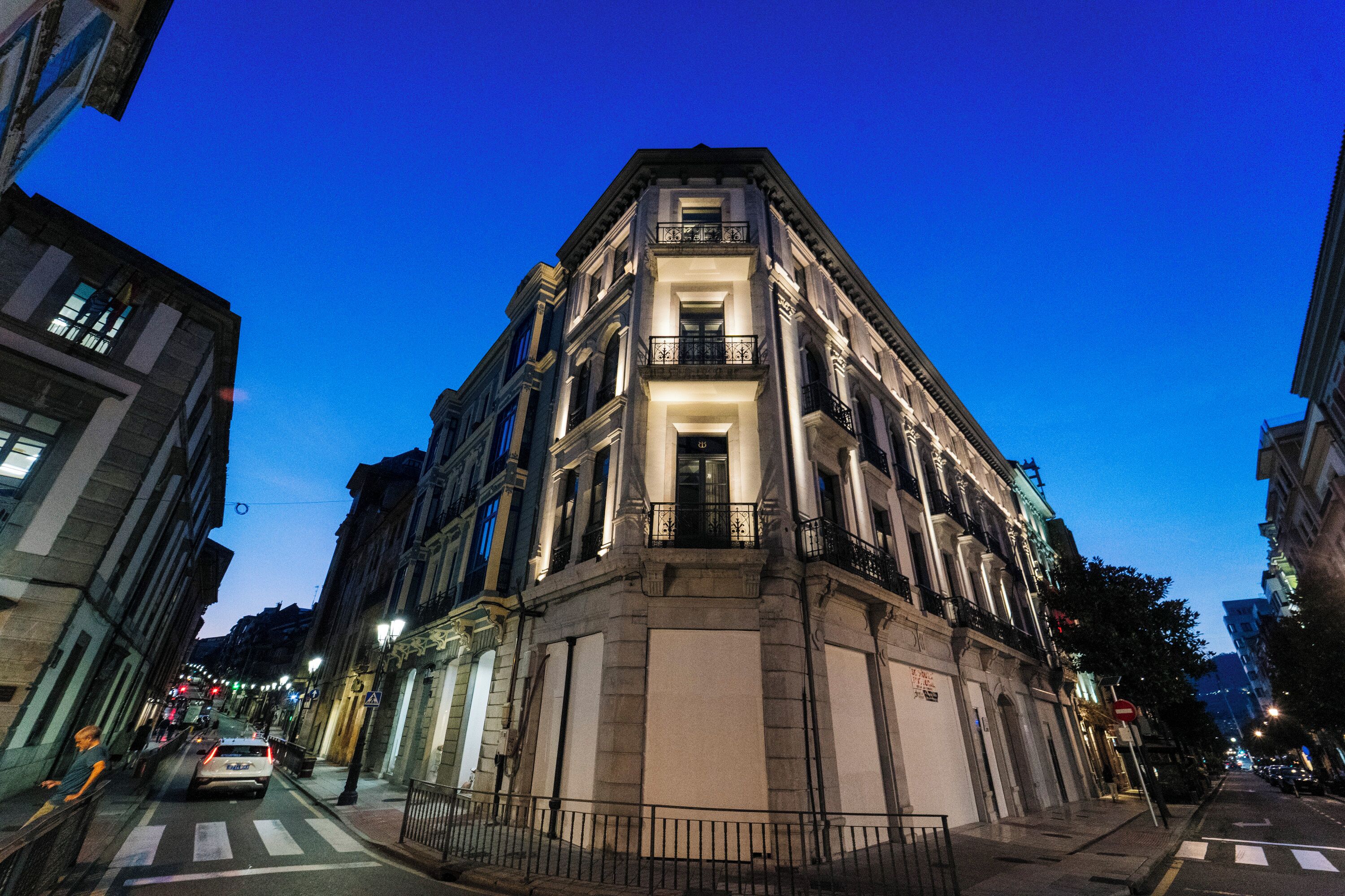A corner building with a classic architectural style, featuring a prominent entrance with a balcony.