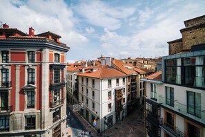 Une vue de rue d’une ville avec des bâtiments historiques, dont un bâtiment à la façade rouge et un autre à la façade blanche.
