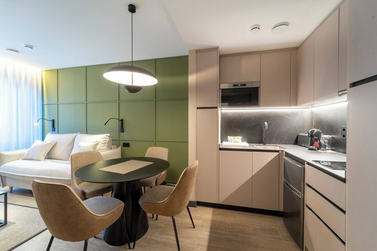 Habitación de hotel moderna con comedor, kitchenette y una cama con vistas.
