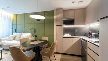 Habitación de hotel moderna con comedor, kitchenette y una cama con vistas.