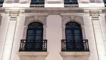 Fachada de edificio con dos ventanas arqueadas simétricas y barandillas negras ornamentales.