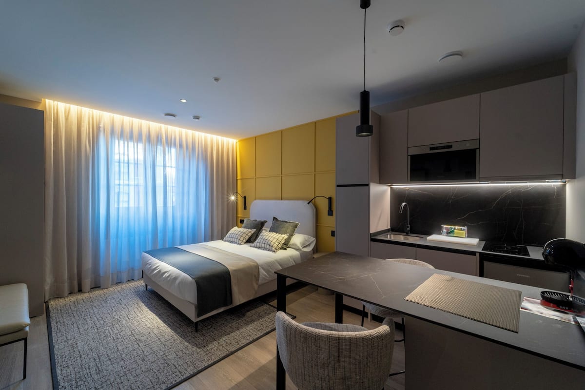 Una habitación de hotel moderna con cama, escritorio y kitchenette.
