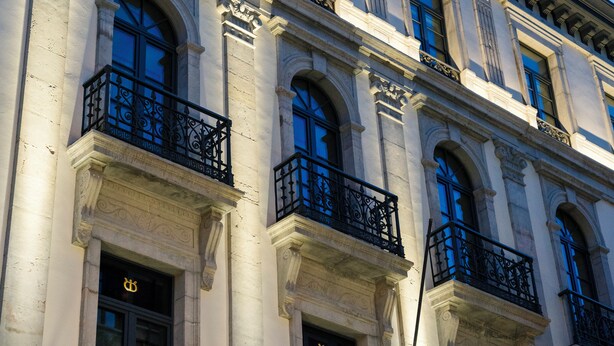 Ein Gebäude mit zahlreichen Fenstern und Balkonen, das klassische architektonische Elemente wie Säulen und dekorative Gesimse aufweist.