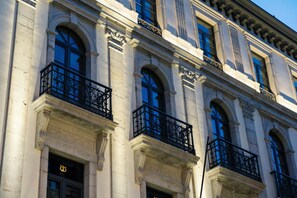 Een gebouw met meerdere ramen en balkons, gekenmerkt door klassieke architecturale elementen zoals zuilen en decoratieve ornamenten.