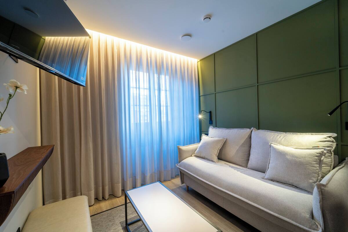 Una sala de estar moderna con un sofá, una mesa de centro y un televisor montado en la pared.