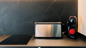 A kitchen counter with a toaster, a coffee maker, and a black electric kettle.