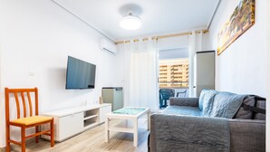 Un salon avec un canapé, un téléviseur, une table et une chaise.