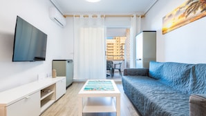 Un salon moderne doté d’un téléviseur à écran plat, d’un canapé, d’une table basse et offrant une vue sur un balcon.