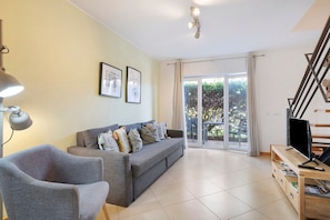 Ein Wohnzimmer mit Sofa, Sessel, Fernseher und Couchtisch.