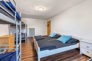Un dormitorio con literas, un escritorio, una silla, un radiador y un armario.