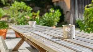 Una mesa de picnic de madera con una taza de cerámica y una pequeña maceta blanca encima.