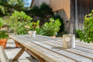 Una mesa de picnic de madera con una taza de cerámica y una pequeña maceta blanca encima.