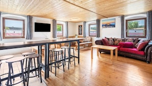 Amplia sala de estar con techo de madera, zona de bar y un sofá con cojines decorativos.