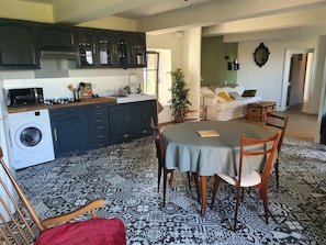 A kitchen with dark cabinets, a washing machine, and a dining area with a table and chairs.