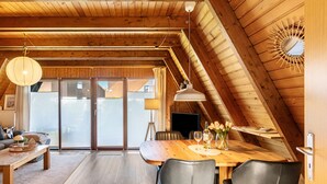 A wooden interior with a dining table, chairs, and a ceiling fan. - Holiday Home Alma – Private Terrace, Wi-Fi, Garden & Coffee Delight Included (Wittmund)