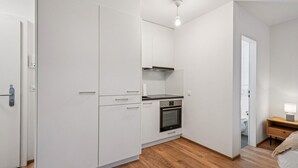 A compact kitchen with white cabinets, a stove, and a microwave. - Exclusive studio near city center - Color 4 (Zürich)