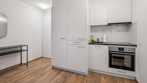 A compact kitchen with white cabinets, a black countertop, a built-in oven, and a wooden floor. - Exclusive studio near city center - Color 4 (Zürich)