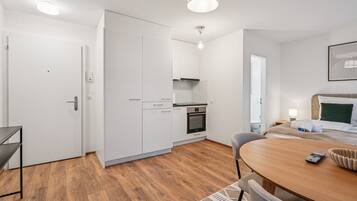 Une chambre d’hôtel compacte comprenant un coin cuisine, un espace repas et un lit avec une tête de lit.