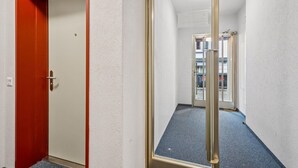 A hallway with a red door, a large mirror, and a carpeted floor. - Exclusive studio near city center - Color 4 (Zürich)
