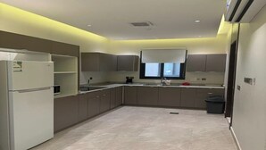 Una cocina moderna con electrodomésticos integrados, una ventana con persianas y suelo de baldosas.