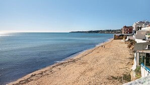 Une plage avec un ciel dégagé, un rivage sablonneux et des bâtiments le long de la côte.