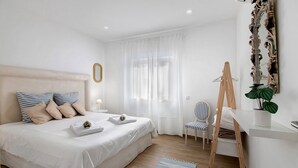 Une chambre bien rangée, avec un lit, une table de chevet, une chaise, un bureau et un miroir.