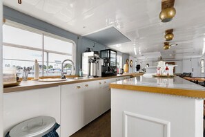 A modern kitchen with a large window, stainless steel appliances, and a wooden countertop. - Boat 'Commodore' with Sea View, Private Terrace and Wi-Fi (Schleswig)