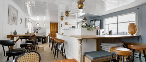 Una cocina moderna con barra, taburetes de madera y vistas por una ventana grande.