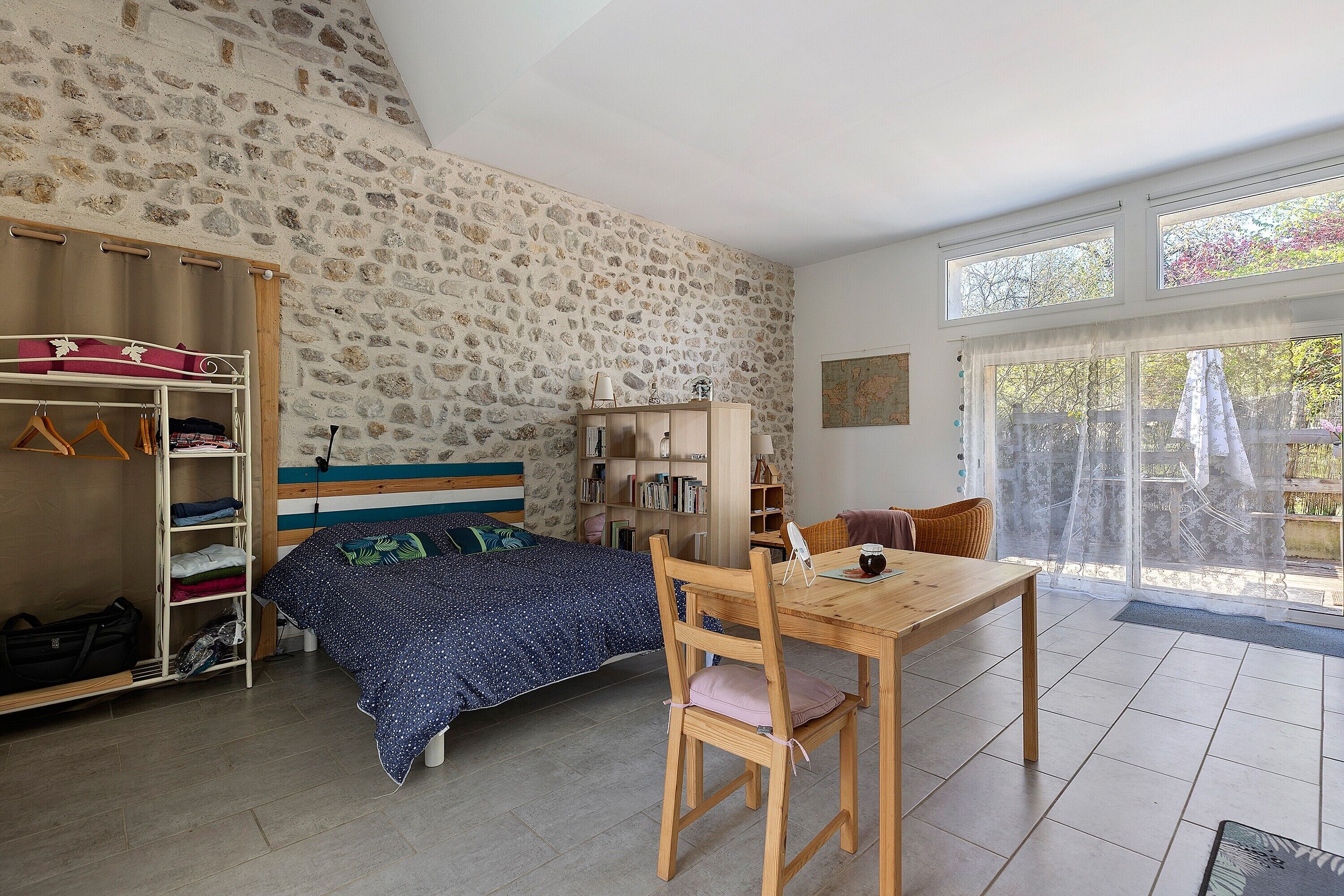 A bedroom with a bed, wooden furniture, a wardrobe, and a dining area.