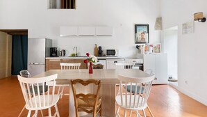 A modern kitchen with white cabinets, a dining table with chairs, and a view of the city. - Maison Bellecour: Shared Terrace, Garden & Wi-Fi in Vaudelnay (Vaudelnay)