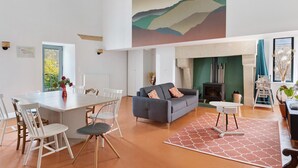A spacious living area with a dining table, chairs, a sofa, a fireplace, and a large abstract painting on the wall. - Maison Bellecour: Shared Terrace, Garden & Wi-Fi in Vaudelnay (Vaudelnay)